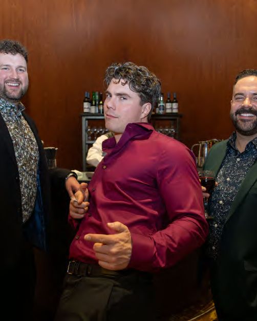 Three guests sharing a joke at a company holiday party, photographed by Dario Hudon