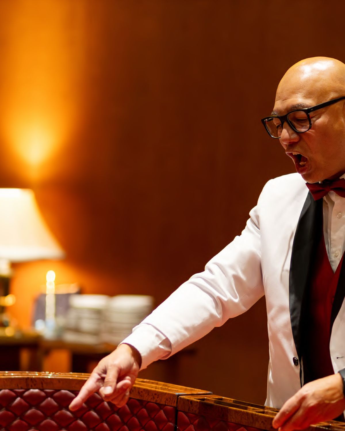 A host in a white dinner jacket running a casino table at a company holiday party, photographed by Dario Hudon